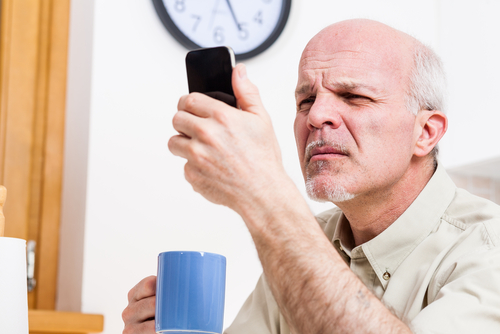 Elderly man with Presbyopia trying to read his cell phone