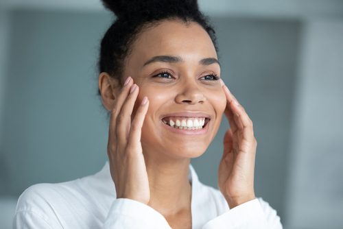 woman smiling and touching her face